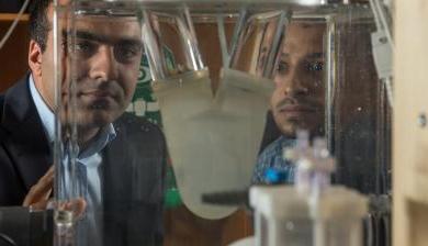 Ali Azadani 和 fellow researcher viewing a biomedical device in Azadani's lab